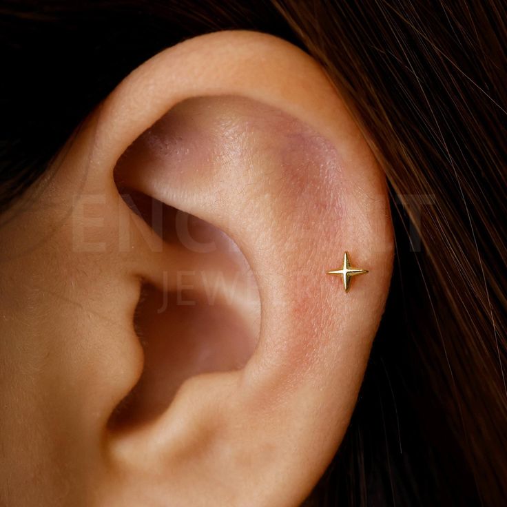 a woman's ear with a tiny cross on it