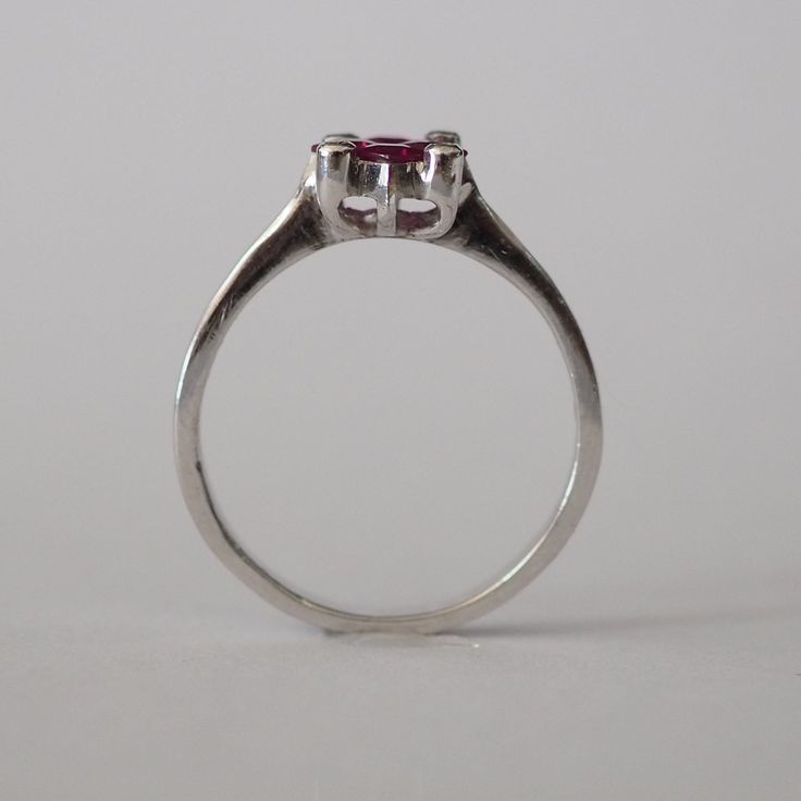 This piece is a wonderful solid white gold ring. It is also a new vintage- made before 2001. The ring is brilliantly decorated with 4 genuine princess cut Chantaburi rubies from Thailand in the middle and on the sides are 4 tiny round cut natural diamond. Only one left- once its gone its gone! Product Details: Metal: 18k Solid Gold Metal Color: White Gold Gold weight: 3.10 grams Ruby: Natural, princess cut, 0.65 carats Diamonds: Natural, round faceted cut, 0.08 carats Band Width: 7 mm #Customiza Classic Ruby Ring With Prong Setting In Platinum, Classic Platinum Ruby Ring With Prong Setting, Classic Platinum Ruby Ring With Brilliant Cut, Classic Platinum Ruby Ring With Center Stone, Classic White Gold Birthstone Ring With Polished Finish, Classic Promise Ruby Solitaire Ring, Classic Solitaire Ruby Promise Ring, Classic Solitaire Ruby Ring For Promise, Classic White Gold Birthstone Promise Ring