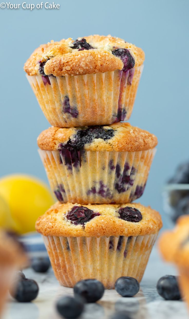 three blueberry muffins stacked on top of each other with lemons in the background