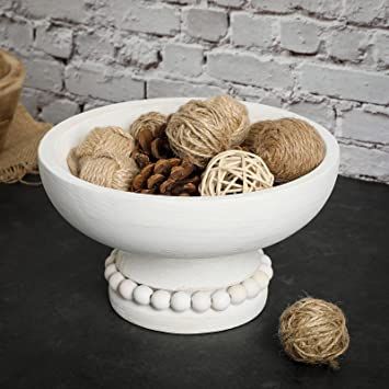 a white bowl filled with balls of yarn on top of a black table next to a brick wall