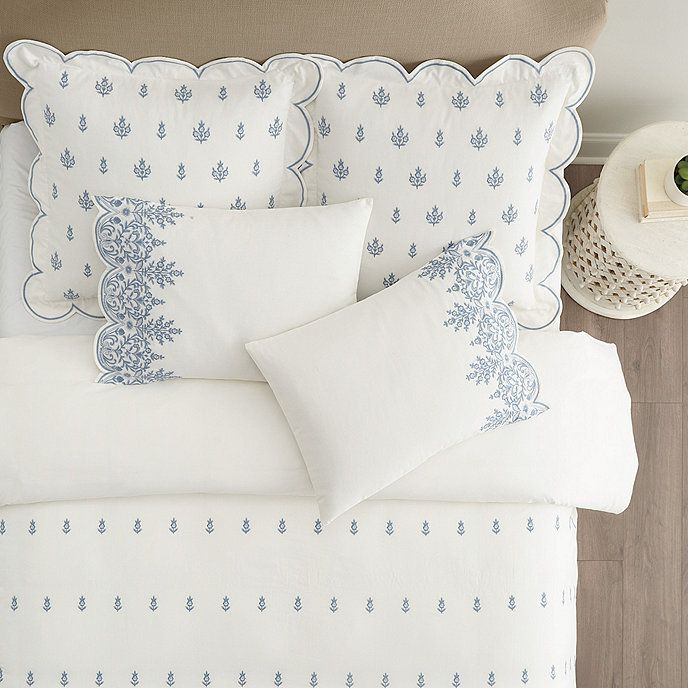 a bed with white and blue comforters on top of it