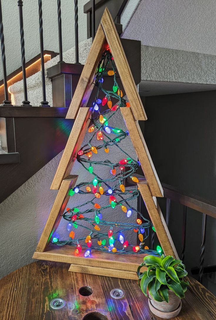 a christmas tree made out of wood with lights on it and some candles next to it