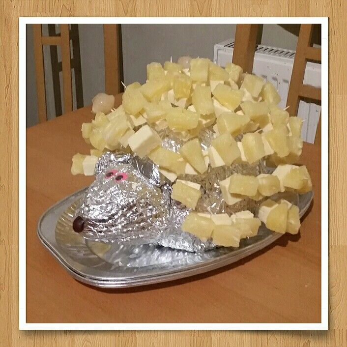 a metal plate topped with cheese covered in tin foil on top of a wooden table