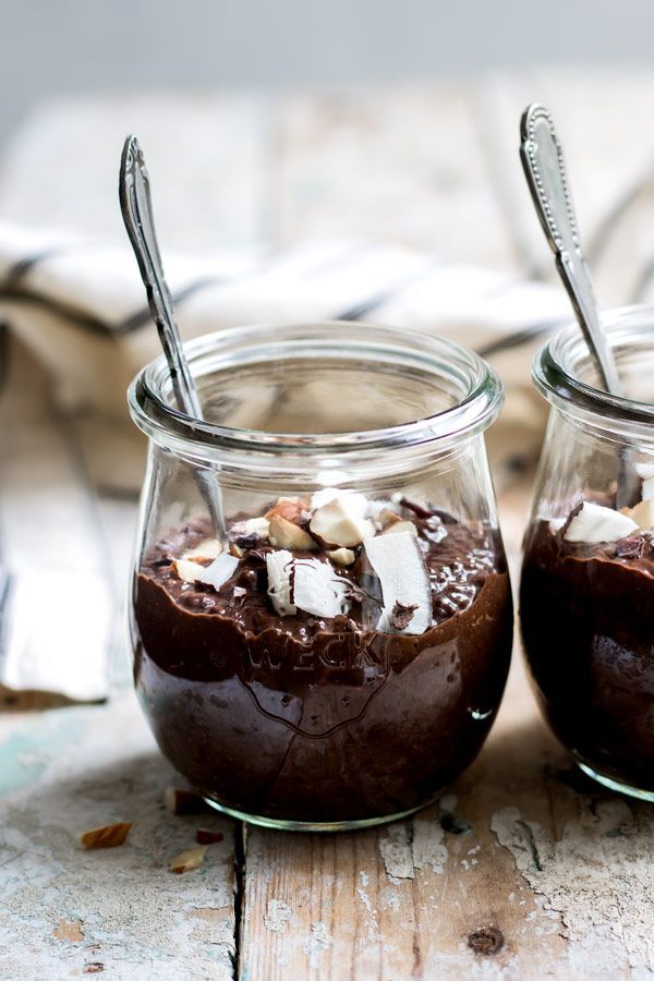 two jars filled with chocolate pudding and marshmallows on top of a wooden table