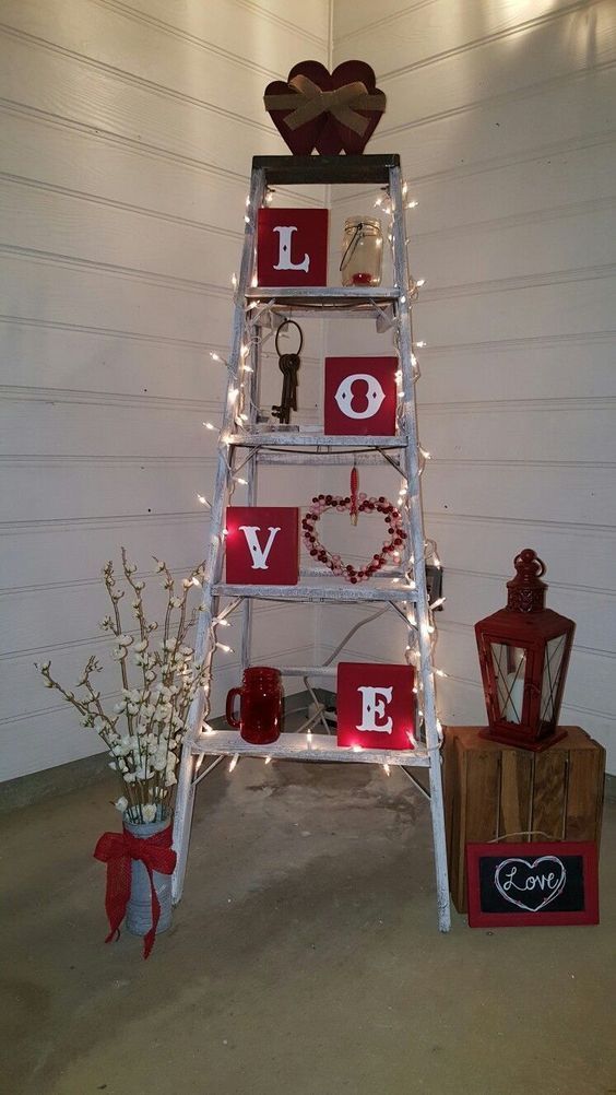 a ladder decorated with valentine's day decorations and lights in front of a white wall