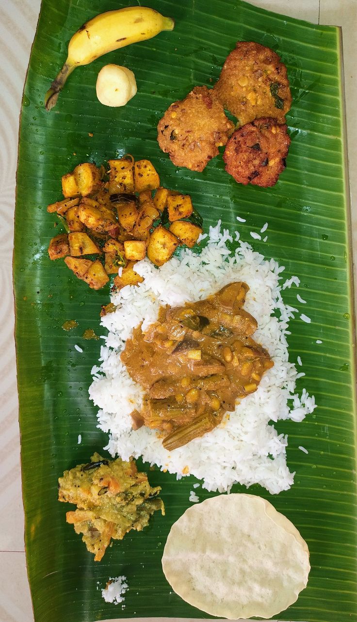 a banana leaf filled with different types of food on top of rice and other foods