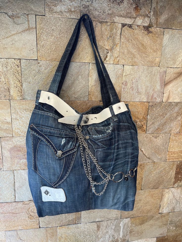 a denim purse with chains hanging from it's front pocket and a tag on the side