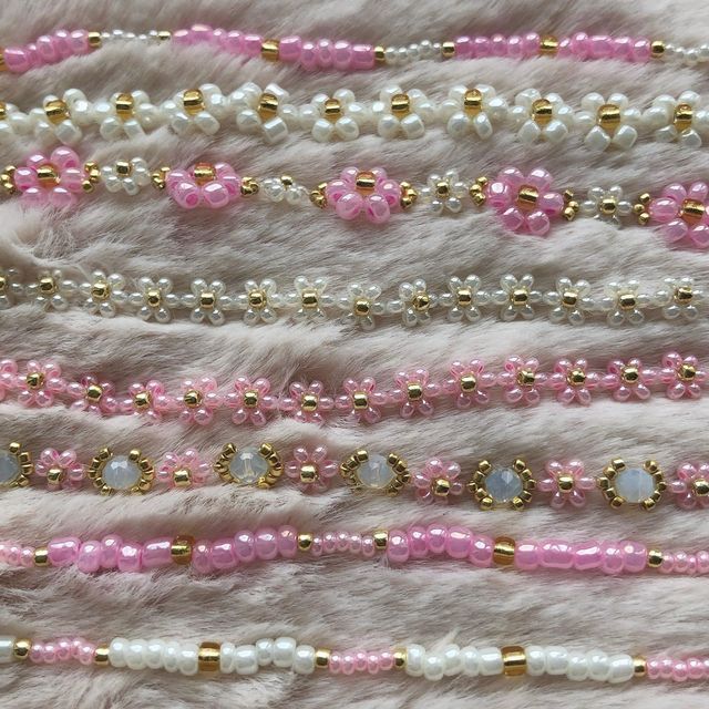 pink and white beaded bracelets are lined up on a fur surface with gold accents