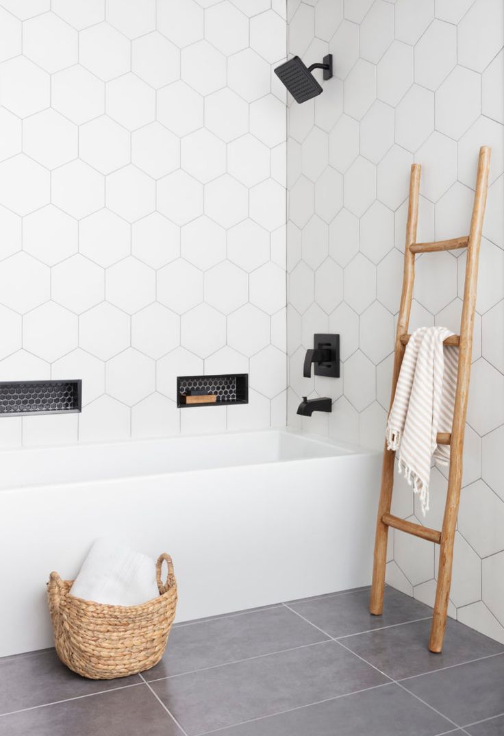 a bathroom with white hexagonal tiles and wooden ladder in the bathtub area