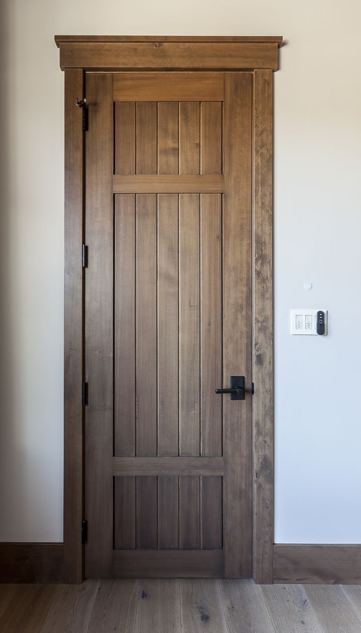 an empty room with a wooden door and white walls