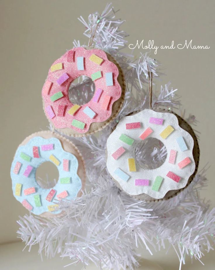 three decorated doughnuts hanging from a white christmas tree