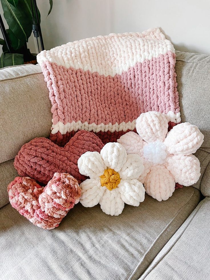 some crocheted flowers are sitting on a couch next to a knitted pillow