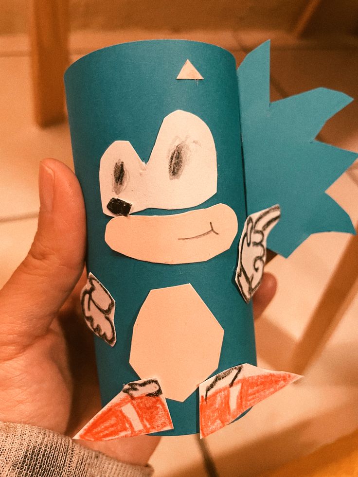 a person holding up a paper cup with an image of a cartoon character on it