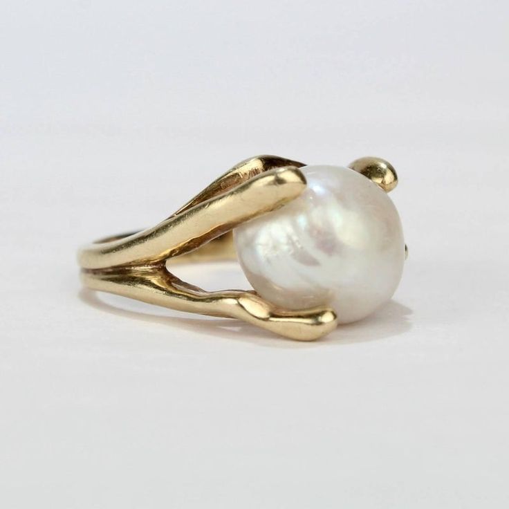 A fine, modernist 14k yellow gold and baroque pearl cocktail ring from the mid-20th century.  Features a large baroque pearl in an organic, pronged setting.  Interior of shank stamped: 14K   Overall Width: ca. 3/4 in. Ring size: 6 1/4  Pearl size:  Ca. 11mm x 13mm    Dimensions reference the ring size and are not specific to the ring itself. Baroque Pearl Engagement Ring, Baroque Pearl Ring, Big Ring Designs, Pearl Rings In Gold, Baroque Ring, Wed Rings, Pearl Ring Gold, Pearls Fashion, Pearl Cocktail Ring