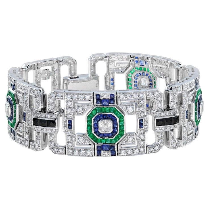 This elegance bracelet reverting "jazz age”. The feel of white gold and the sparkle from the diamonds and gemstones all come together perfectly in this magnificent details. The bracelet features four open geometric panels set with Asscher cut diamonds, emeralds, blue sapphires and onyx, all set in 18k white gold with fine milgrain work. Bracelet Information Metal: 18K White Gold Width: 22 mm. Length: 192 mm. Weight: 69.19 g. (approx. in total) Center Gemstone Type: Diamond Shape: Asscher Average Luxury White Platinum Bracelets, Luxury White Gold Bracelet With Gemstone, Luxury Jeweled White Sterling Silver Bracelet, Luxury Diamond Gemstone Bracelets, Luxury Diamond Gemstone Bracelet, Luxury Diamond Bracelets With Gemstones, Elegant Multi-stone Bangle Bracelets, Art Deco White Gold Bracelets For Evening, Luxury White Sterling Silver Bracelet