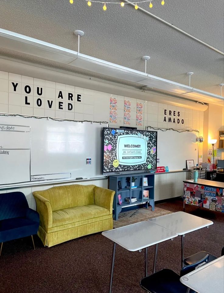 an empty classroom with chairs, desks and a television on the wall that says you are loved