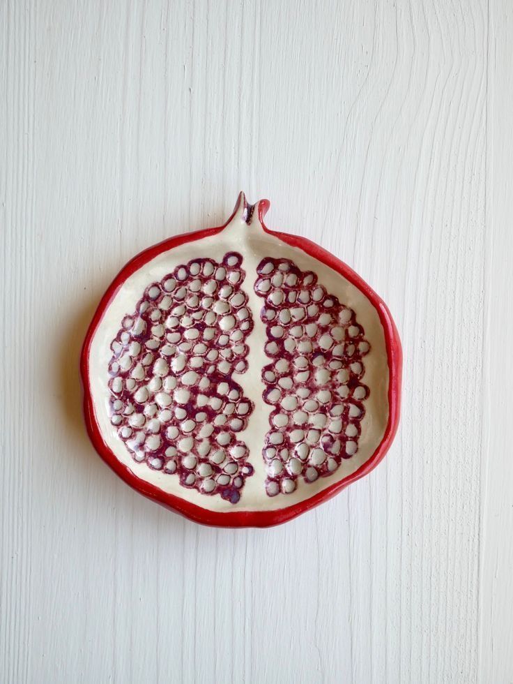 a pomegranate on a white table with red trimmings and beads