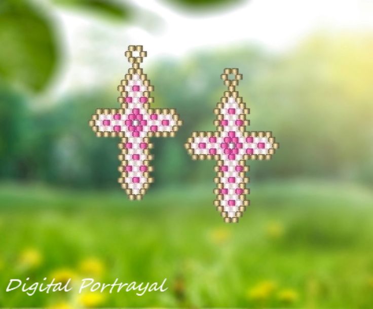 two pixelated cross earrings sitting on top of a green grass covered field with yellow flowers