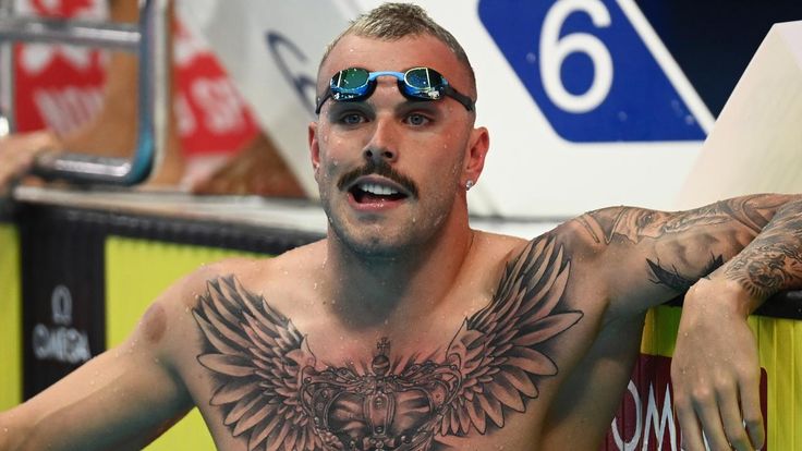 a man with tattoos on his chest and arms is standing next to a swimming pool