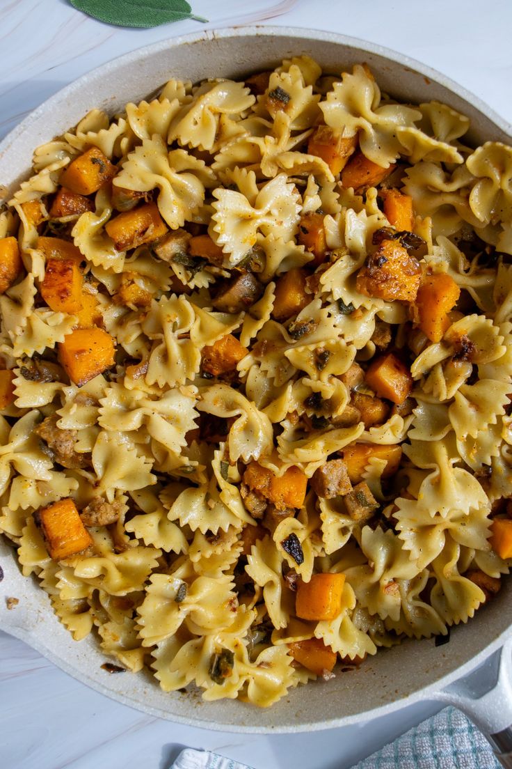 a bowl filled with pasta and carrots on top of a table