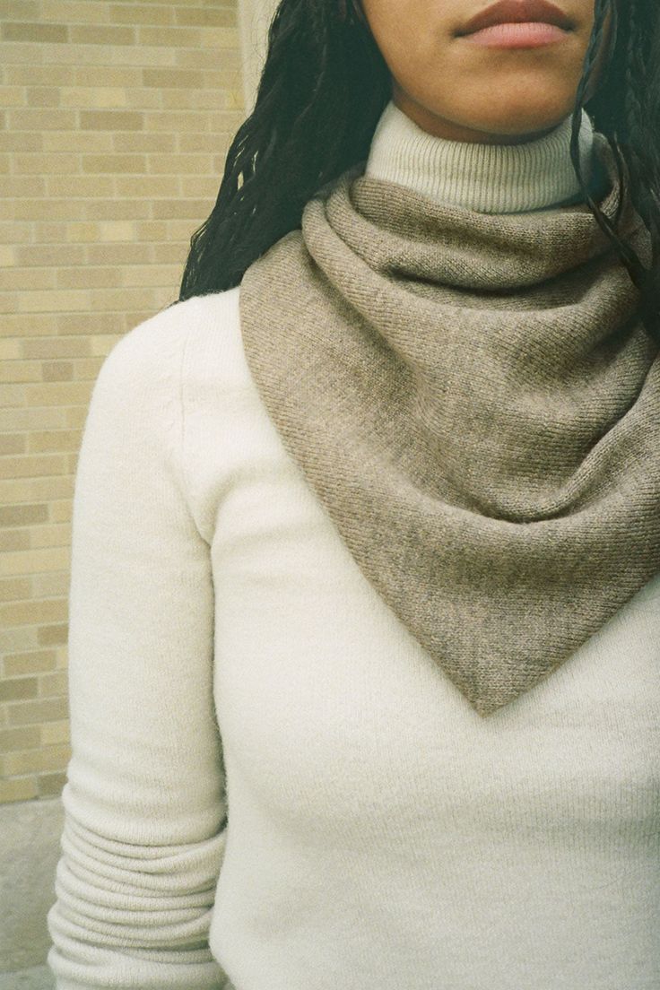 a woman with long hair wearing a white turtle neck sweater and scarf around her neck