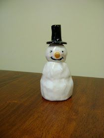 a small white snowman sitting on top of a wooden table