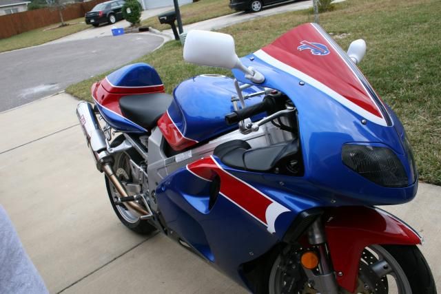 a red, white and blue motorcycle parked on the sidewalk