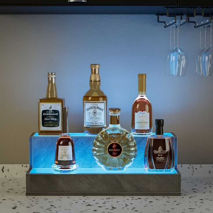 several bottles of liquor are on a blue lighted shelf