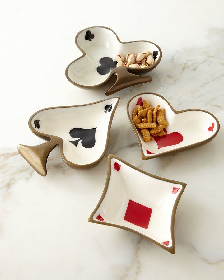 four heart shaped dishes with playing cards and chips in them on a marble countertop