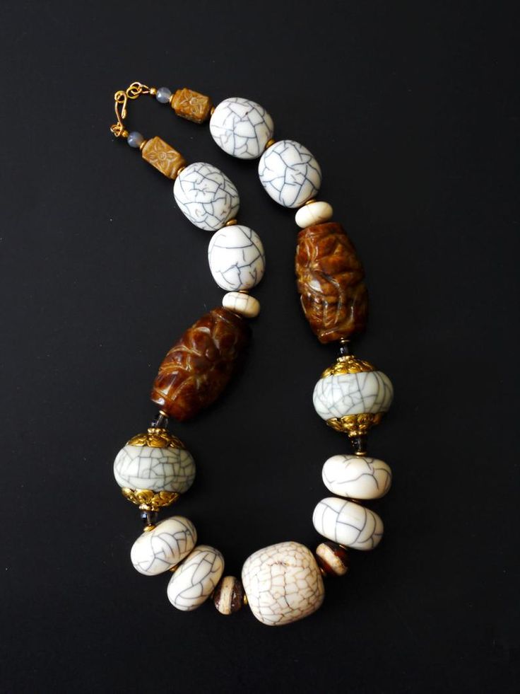 a white and brown beaded necklace on a black surface