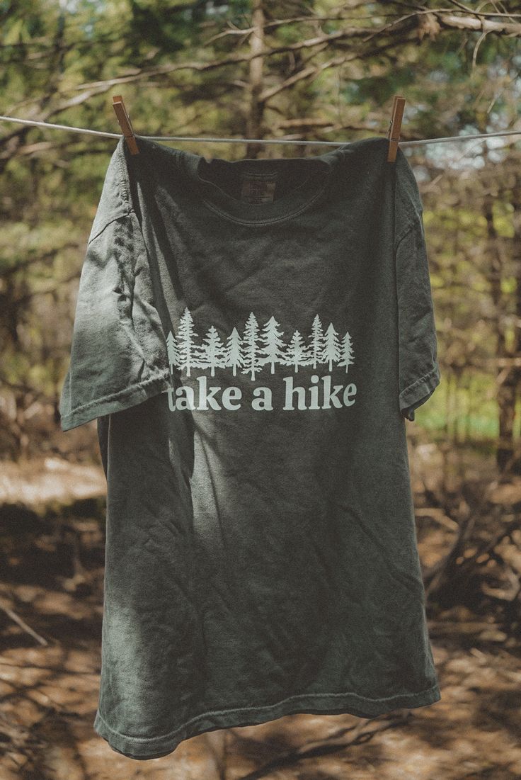 Take A Hike graphic t-shirt. Each t-shirt is pressed house on a comfort colors unisex shirt. T-shirts are made of a soft cotton blend and features a vibrant direct to fabric transfer design that won't fade or crack. COLOR PICTURED: HEMP Shop our wanderlust inspired t-shirt collection. Perfect for those who enjoy hiking, camping, exploring the outdoors and all adventure seeking enthusiasts. keywords: take a hike, outsider hiking shirt, wanderlust t-shirt, adventure t-shirts, graphic tees, unisex Take A Hike Shirt, Cotton Crew Neck T-shirt For Outdoor Activities, Green Graphic Print T-shirt For Camping, Custom Print Short Sleeve T-shirt For Outdoor, Outdoor Relaxed Fit T-shirt With Text Print, Green T-shirt For Outdoor Activities, Pre-shrunk Green T-shirt For Camping, Outdoor Green T-shirt With Graphic Print, Green Graphic Print Outdoor T-shirt