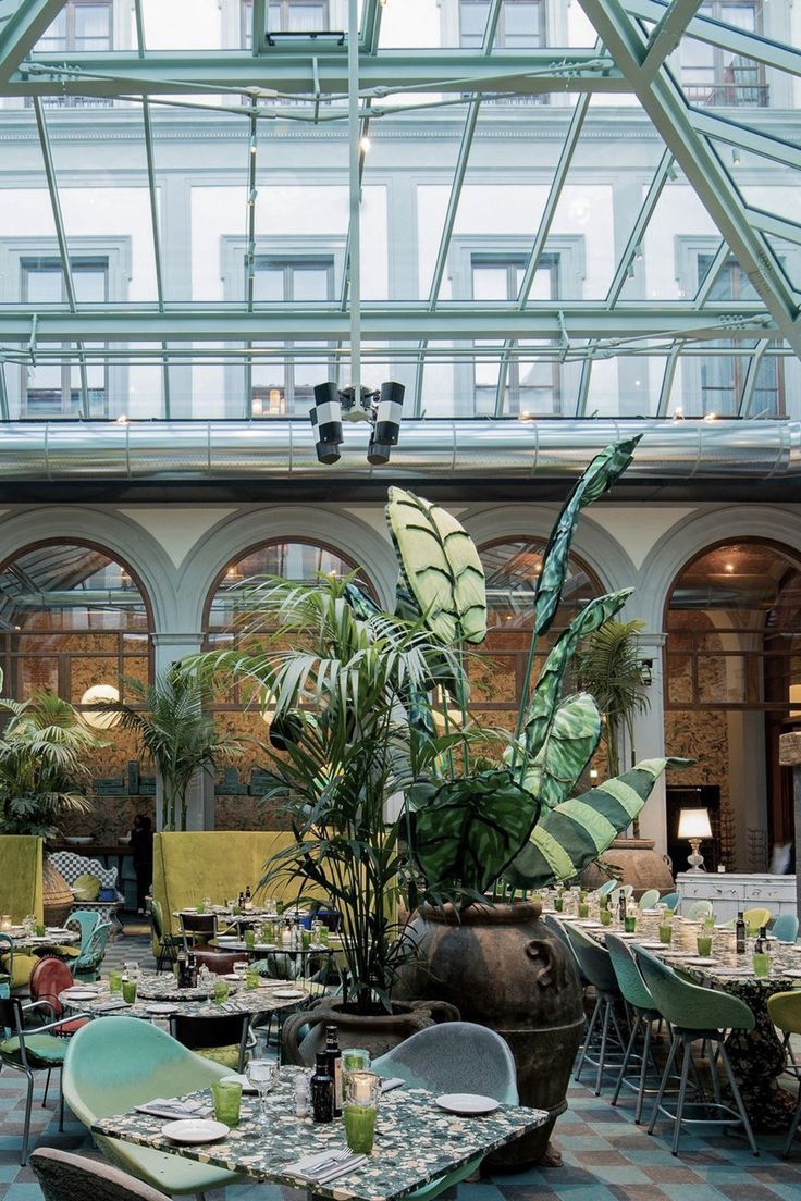 an indoor dining area with tables, chairs and potted plants in the center of the room