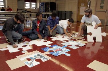 several people are assembling puzzle pieces on the floor