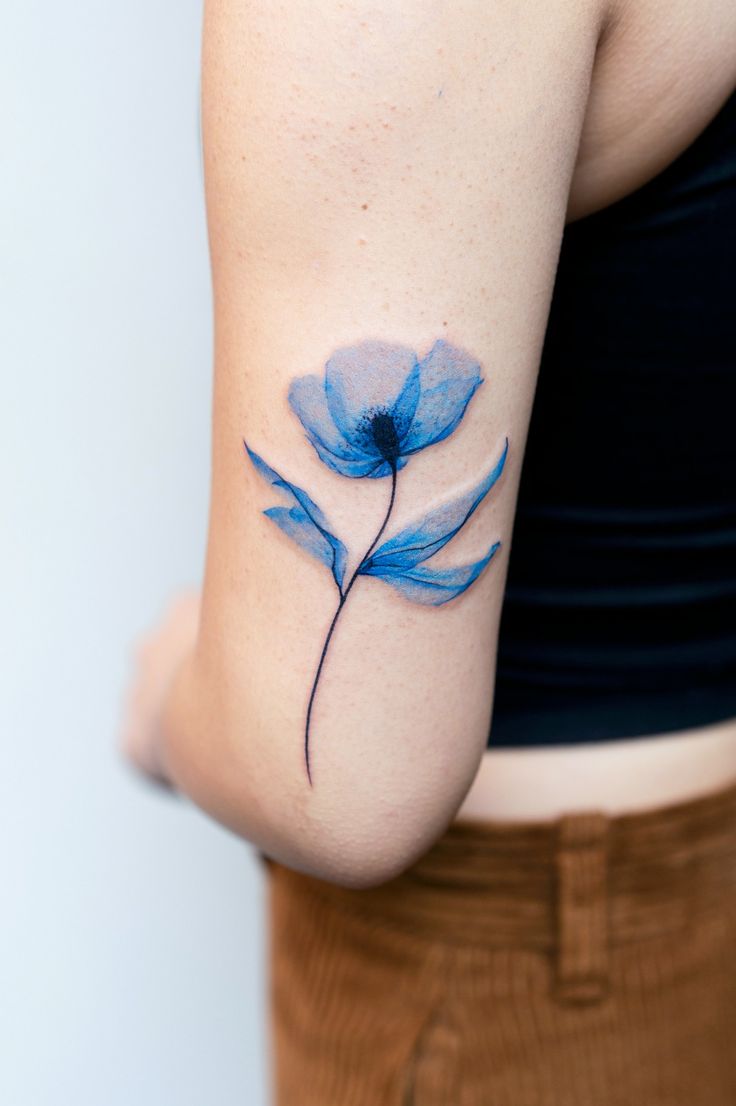 a blue flower tattoo on the left side of the right arm is shown in front of a woman's stomach