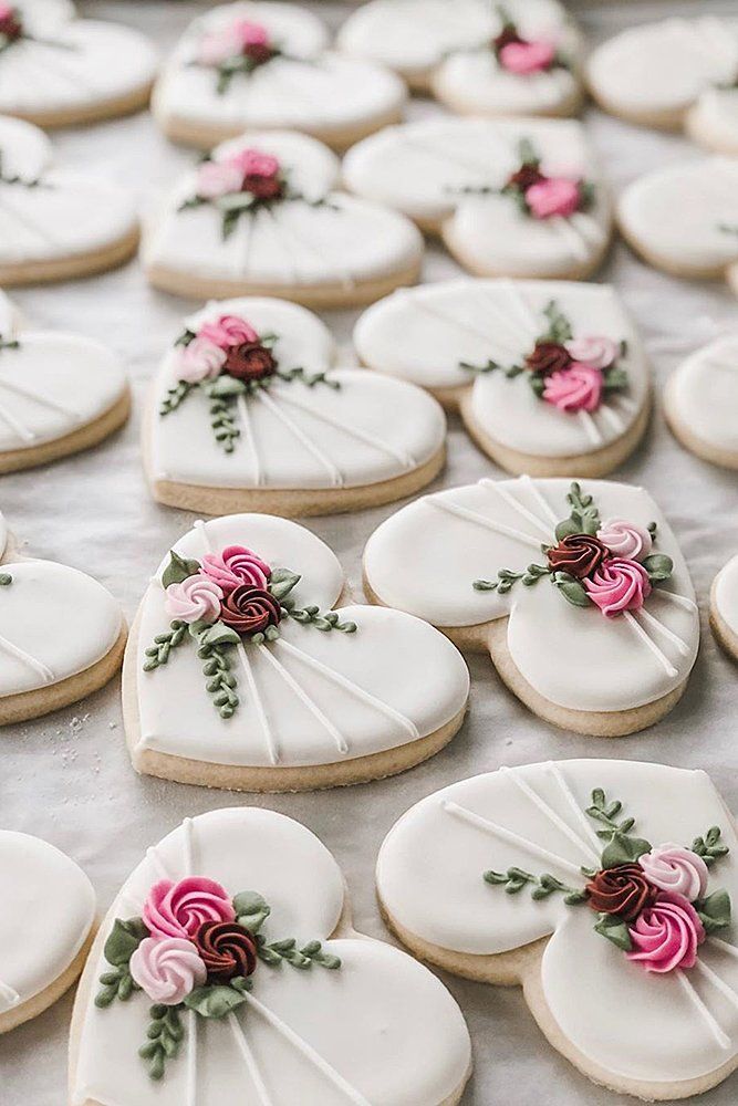 decorated heart shaped cookies on a table with pink and red flowers in the middle,