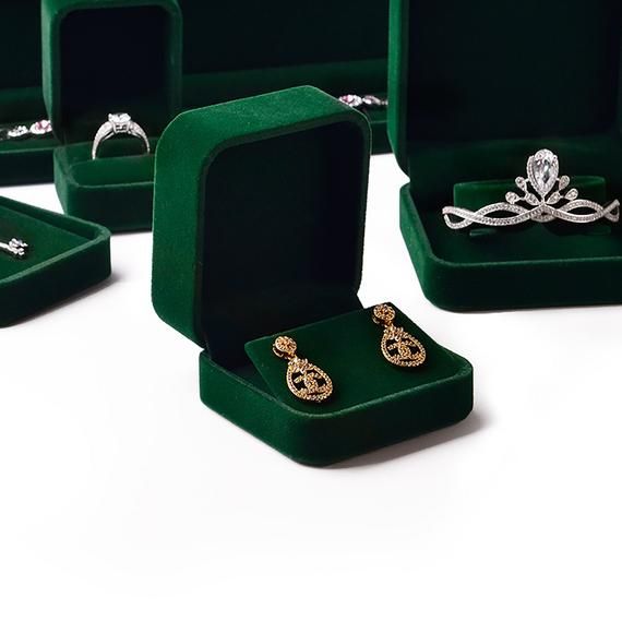 several different types of rings in green velvet cases on white surface with one open and the other closed