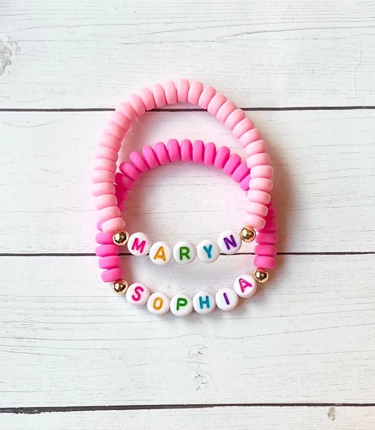 two pink and white bracelets with the words happy birthday spelled in small letters on them