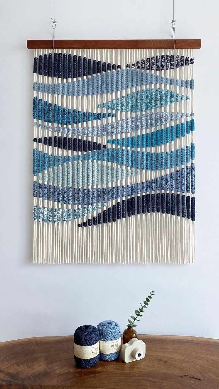 a blue and white wall hanging next to two crocheted balls on a wooden table