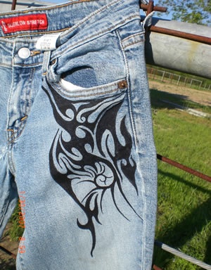 a pair of blue jean shorts with black and white designs on them, in front of a fence