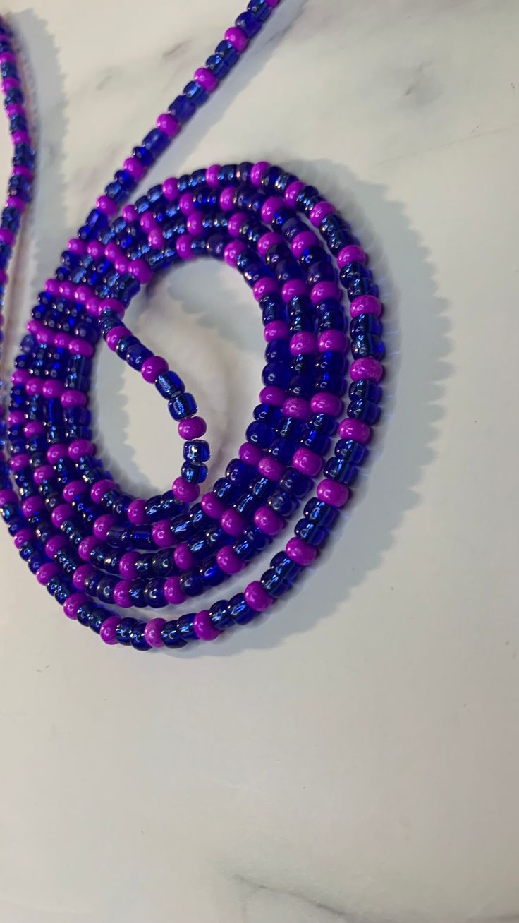 Handcrafted waist beads in our blue and purple. All waist beads are made with glass seed beads. Our tie-on waist beads come with cotton beading string from Ghana, and our removable clasp, options comes with our extra strong elastic threading. All waist beads are made to order.  Our waist beads come in the traditional tie-on method and a clasp method. The tie-on method is for permanent everyday wear. The clasp method is for the unicorns who like to be versatile and take their waist beads off whenever they choose.  MEASURING YOUR WAIST Please measure your waist in the area where you would like your waist beads to fall. Waist beads can be worn at the hipline and the natural waistline.  After measuring your waist please add at least a one to a two-finger gap for a comfortable fit. Blue Waist Beads With Spacer Beads As Gift, Blue Colorful Waist Beads As Gift, Blue Beaded Waist Beads As Gift, Blue Round Beads Waist Beads For Gift, Blue Waist Beads Gift, Blue Beaded Waist Beads, Blue Round Beads Waist Beads For Festival, Handmade Blue Waist Beads As Gift, Purple Beaded Chain Bracelets For Festival