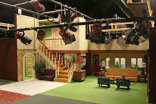 a set with chairs, couches and lights on the ceiling in front of stairs