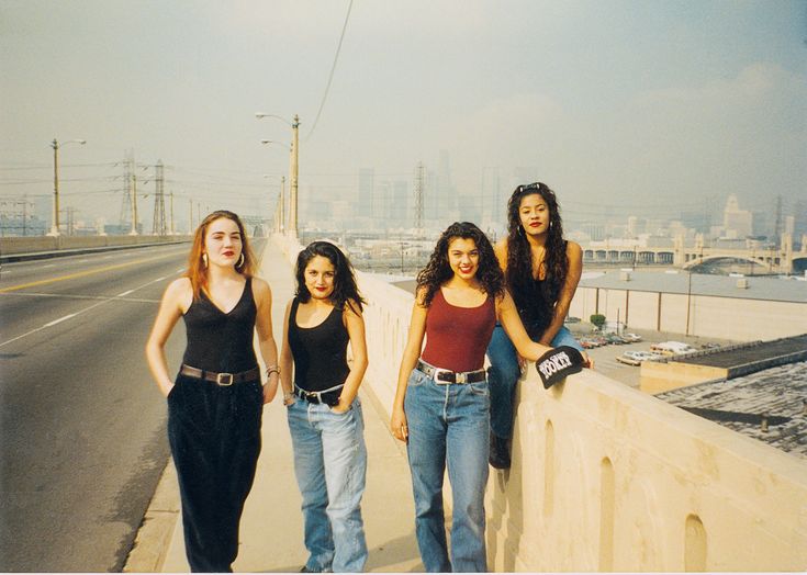 four women standing on the side of a bridge