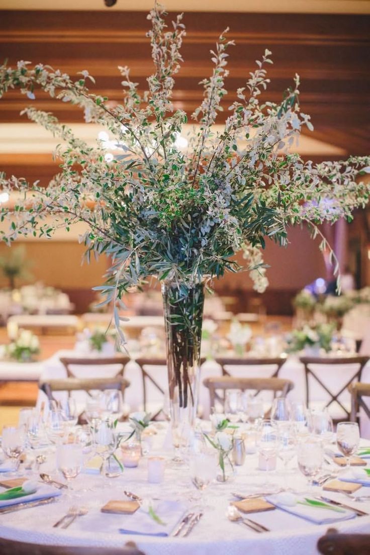 a vase filled with lots of flowers on top of a white table cloth covered table