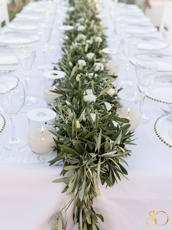 a long table with candles and greenery on it