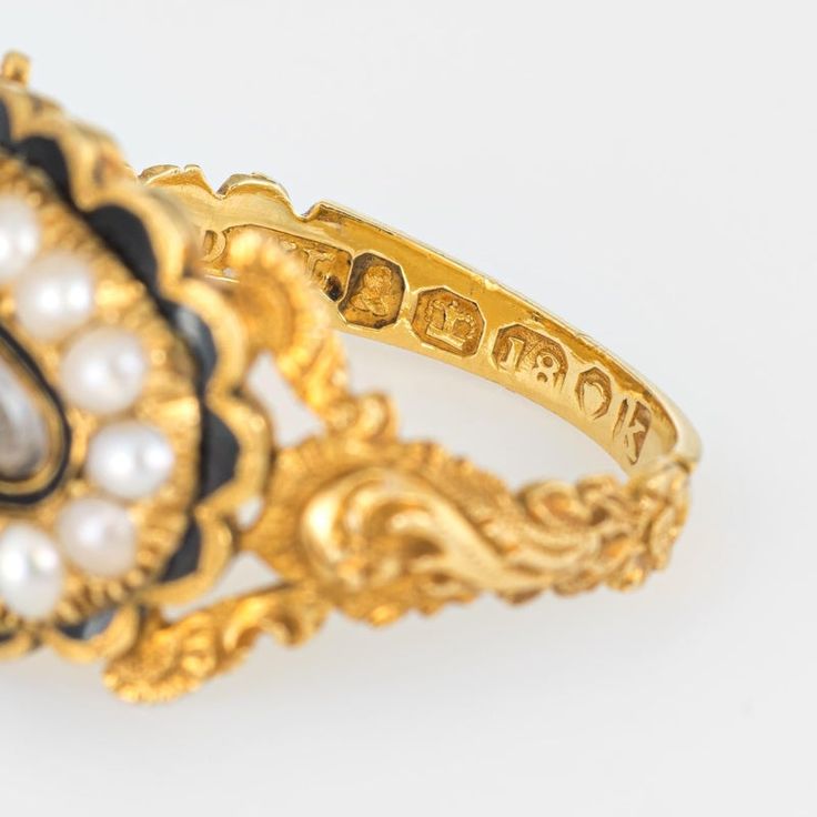 Antique Georgian era memorial ring (circa 1825) crafted in 18 karat yellow gold.   Natural pearls measuring (average) 2.5mm border an oval compartment that holds natural hair. The pearls are in very good condition showing good lustre. The glass case protecting the braided hair is in excellent condition and free of cracks or crisps.       The ring is a wonderful example of Georgian era memorial jewellery with rich floral and scrolled details to the side shoulders. The pearls border a lock of hair Antique Yellow Gold Pearl Ring With Rose Cut Diamonds, Victorian Oval Cabochon Pearl Ring, Vintage Gold Pearl Ring With Rose Cut Diamonds, Elegant Gold Ring With Historical Design, Gold Cabochon Signet Ring For Wedding, Gold Pearl Cabochon Ring For Wedding, Gold Cabochon Pearl Ring For Wedding, Gold Oval Enamel Ring With 17 Jewels, Victorian 14k Yellow Gold Pearl Ring