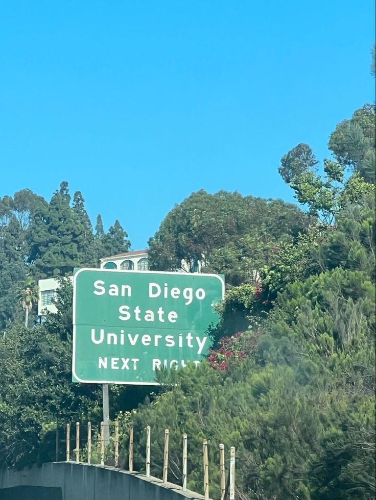 a freeway sign on the side of a road with trees and bushes in the background