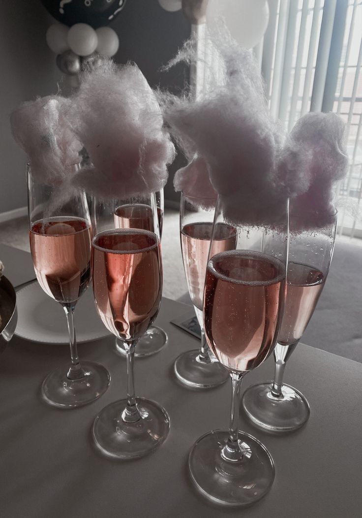 four wine glasses filled with pink liquid and cotton floss are sitting on a table