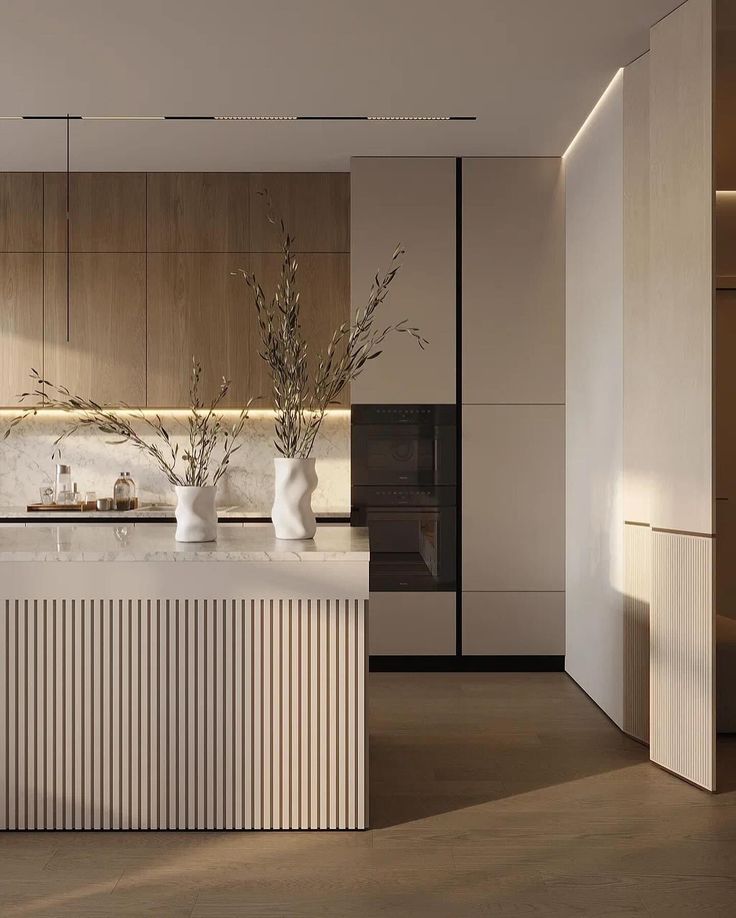 a modern kitchen with marble counter tops and white vases filled with flowers on the island