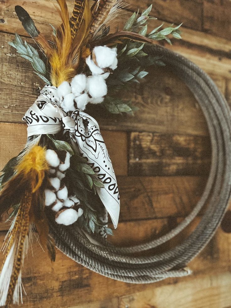 a wreath with cotton and feathers on top of a wooden table next to a rope