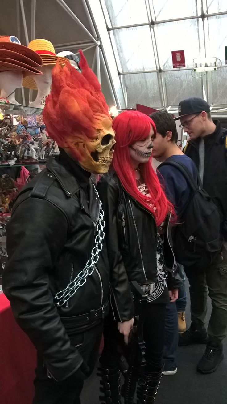 two people dressed up in costumes and chains at a convention or show, one is wearing a skull mask